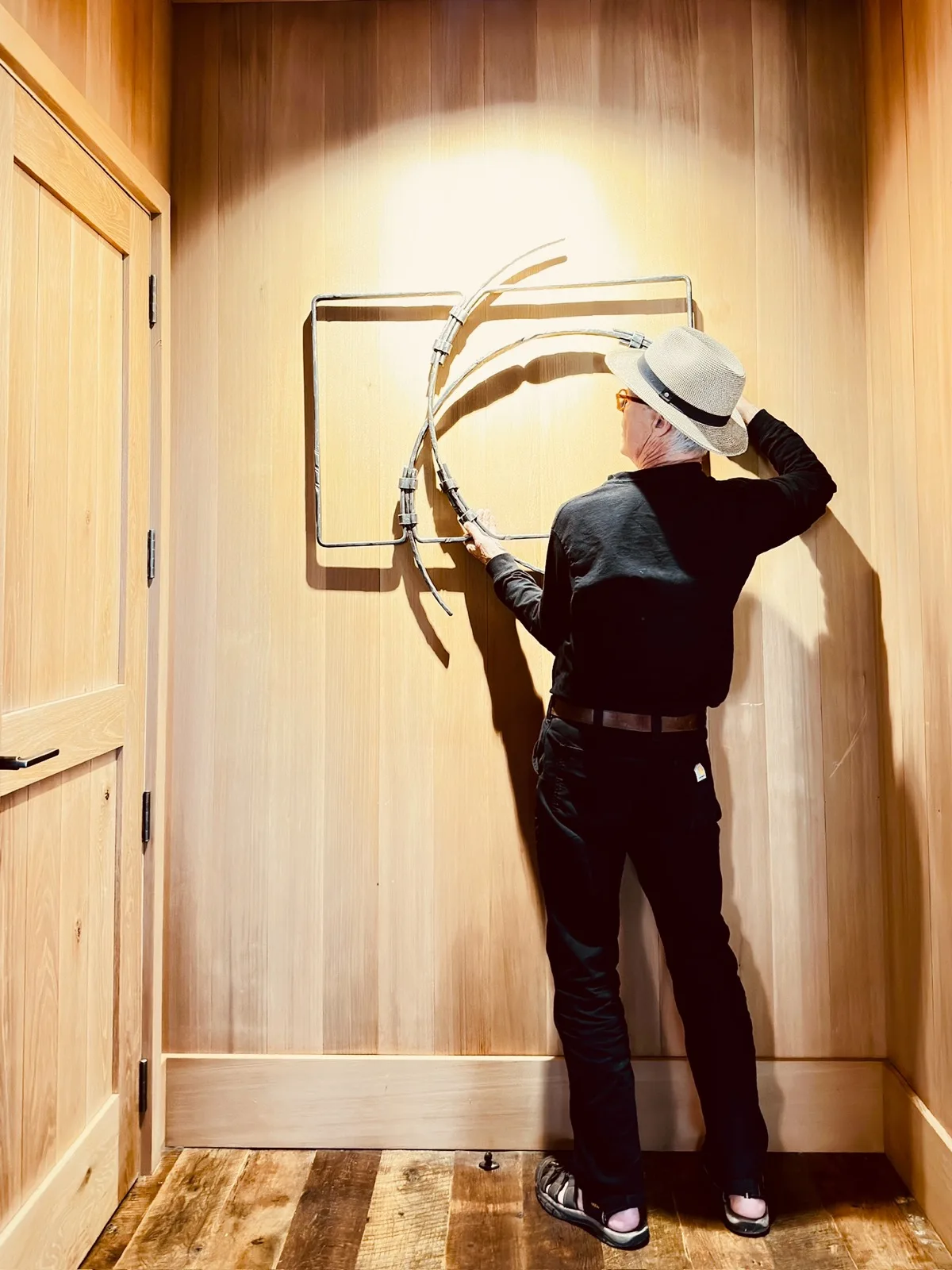 Jefferson Mack hanging a forged piece on a cedar wall